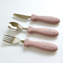 Load image into Gallery viewer, the stainless steel kids cutlery set showing a fork, spoon and knife in rose silicone with the calf & crew logo