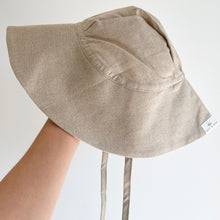 Load image into Gallery viewer, a hand holding up the floppy sun hat in sand