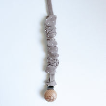 Load image into Gallery viewer, a cotton scrunch dummy clip in dottie latte colour with the elephant logo on the wooden clip
