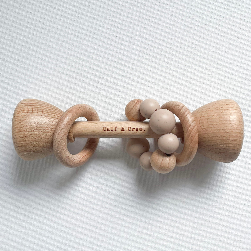 a wooden rattle with a chai silicone teether ring and the calf & crew logo engraved on the center