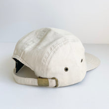 Load image into Gallery viewer, the back of the crew cap patch in cream showing the adjustable strap