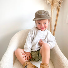 Load image into Gallery viewer, child sitting in a soft white chair wearing the embroidered crew cap in khaki colour