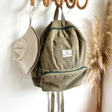 Load image into Gallery viewer, a everyday sunhat in sand hanging on a wooden hook with a khaki coloured corduroy backpack