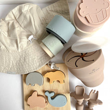 Load image into Gallery viewer, The everyday sun hat in sand colour with silicone stacking cups spilled to the side, a collapsible snack cup and easy grip spoon and fork in latte colour and a silicone animal puzzle