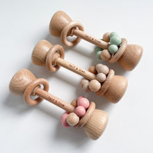 Load image into Gallery viewer, three wooden silicone rattles lined up in blush, chai, and mint colours
