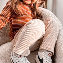 Load image into Gallery viewer, a child sitting in a soft chair showing the ribbed straight fit leggings in beige