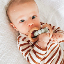 Load image into Gallery viewer, a baby laying down chewing on the wooden silicone ring teether in mint colour