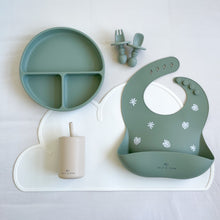 Load image into Gallery viewer, Divided plate, small fork and spoon, and silicone bib in forest green, laying on a white mat with a silicone straw cup in sand colour