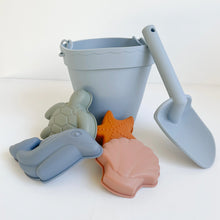 Load image into Gallery viewer, the silicone beach toy set in ocean colour showing blue bucket and spade, and shape moulds of a green turtle, blue dolphin, orange starfish and pink seashell