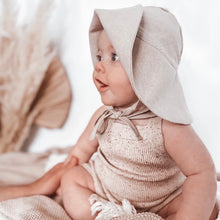 Load image into Gallery viewer, a baby sitting wearing the floppy sun hat in sand colour with it flipped up showing the side view