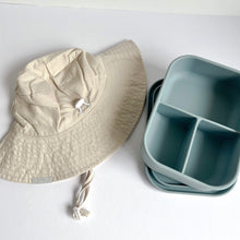 Load image into Gallery viewer, a folded everyday sun hat in sand colour with a open silicone bento lunchbox in baby blue colour