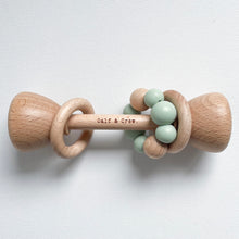 Load image into Gallery viewer, a wooden rattle with a mint silicone teether ring and the calf &amp; crew logo engraved on the center
