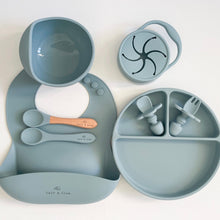 Load image into Gallery viewer, a suction bowl, a bib, a silicone spoon, a beechwood spoon, a collapsible snack cup, a suction divider plate, and easy grip cutlery all in baby blue silicone colour