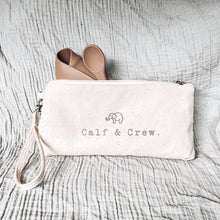 Load image into Gallery viewer, the tucker time satchel showing the calf &amp; crew logo with a latte coloured folded bib and spoon 
