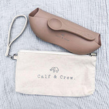 Load image into Gallery viewer, the tucker time satchel with the calf &amp; crew logo laying next to a folded latte coloured bib and spoon
