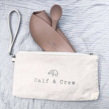 Load image into Gallery viewer, a latte coloured folded bib and spoon going into a tucker time satchel
