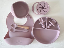 Load image into Gallery viewer, a suction bowl, a bib, a silicone spoon, a beechwood spoon, a collapsible snack cup, a suction divider plate, and easy grip cutlery all in rose silicone colour
