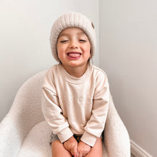 Load image into Gallery viewer, a toddler sitting sticking his tongue out wearing the crew sweatshirt in eggnog and toddler beanie in oatmeal
