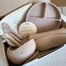 Load image into Gallery viewer, A box with a beige pouch, 3 spoons, a wooden plaque engraved with &quot;my first solids&quot;, a silicone divided plate, sucion bowl and bib in latte colour
