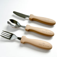 Load image into Gallery viewer, the stainless steel kids cutlery set showing a fork, spoon and knife in latte silicone with the calf &amp; crew logo
