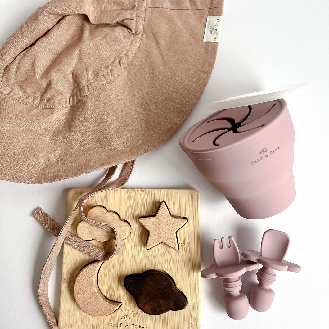 the floppy sun hat in rose colour with the wooden night sky puzzle, and a collapsible snack cup and easy grip spoon and fork in rose colour