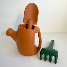 Load image into Gallery viewer, Terracotta silicone garden set showing orange watering can and spade and a green rake
