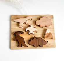 Load image into Gallery viewer, a wood base with wooden dinosaur puzzle shapes 
