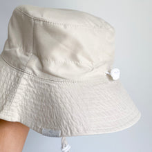 Load image into Gallery viewer, hand holding up the sun hat in sand colour showing the adjustable strap
