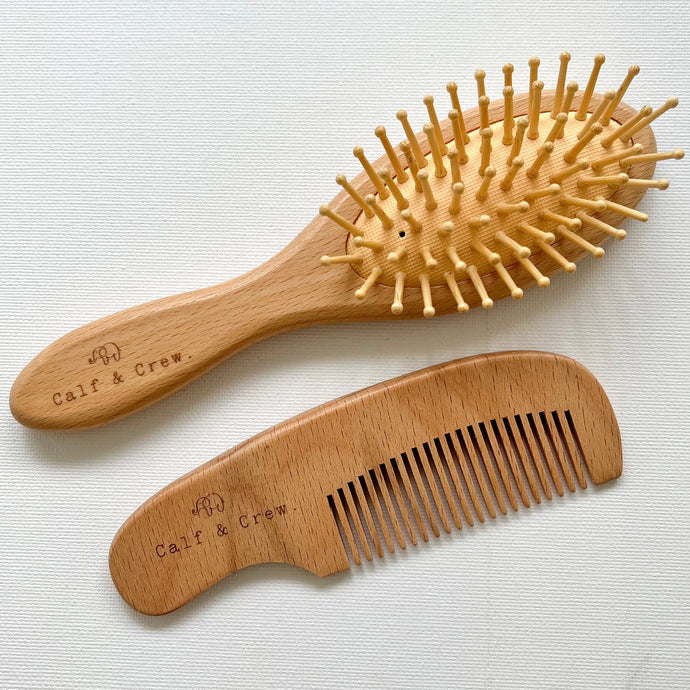 a wooden brush and wooden comb both with the Calf & Crew logo engraved on the handle