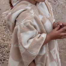 Load image into Gallery viewer, close up of a child wearing the hooded terry beach towel on the sand
