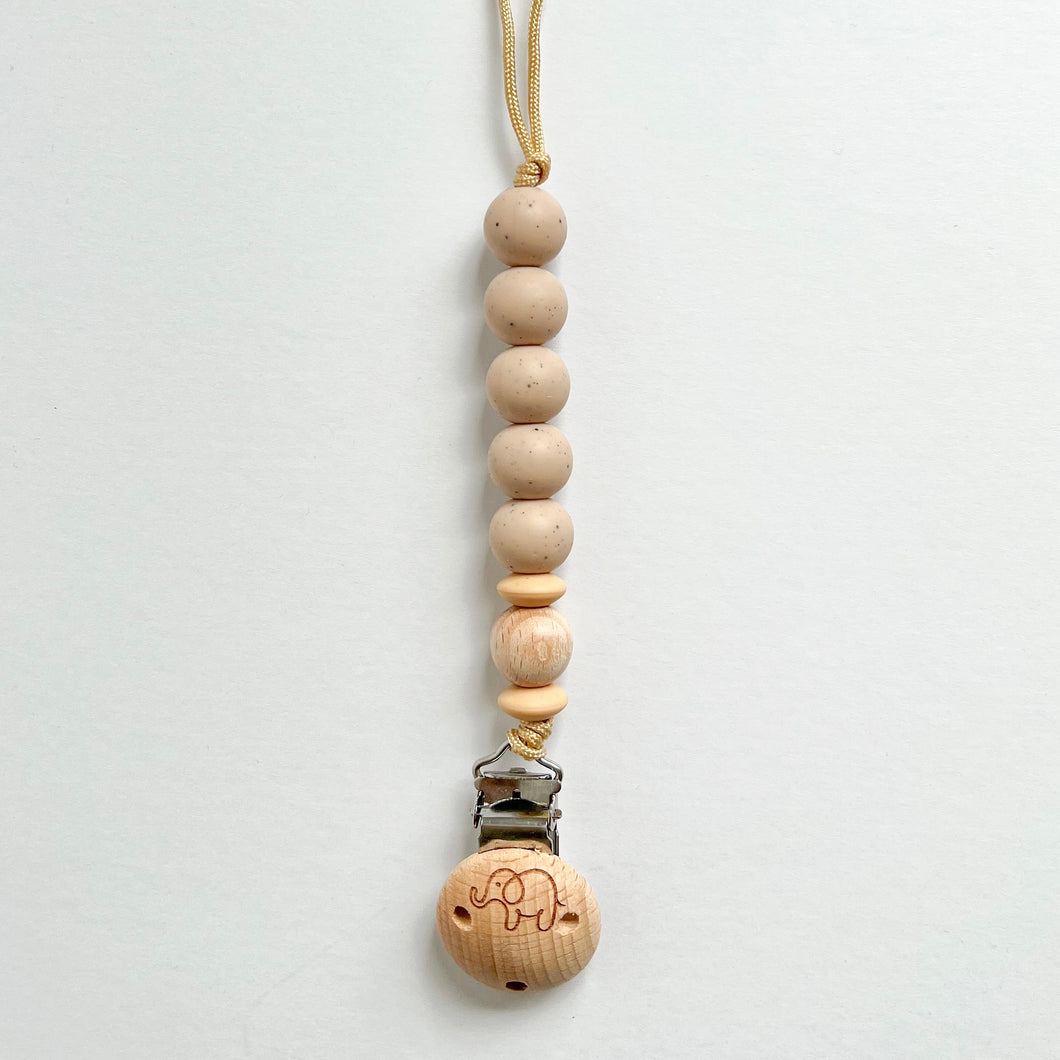 the silicone dummy clip in chai colour showing the elephant engraved wooden clip