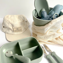 Load image into Gallery viewer, the crew cap in cream with the silicone beach set in palm breeze colour, with an open silicone bento lunchbox in sage, and a stainless steel spoon, fork and knife in sage colour
