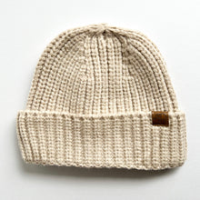 Load image into Gallery viewer, a chunky knit toddler beanie in oatmeal colour with a leather  calf &amp; crew logo
