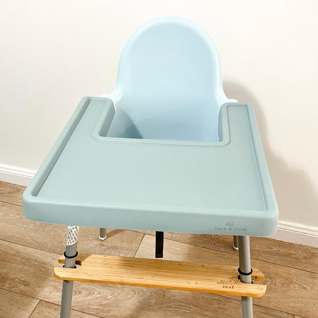 a sage silicone high chair table cover on a white ikea highchair