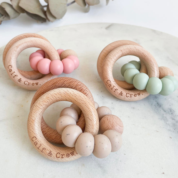 three wooden silicone ring teethers in blush, mint and chai