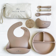 Load image into Gallery viewer, Beige pouch with Calf &amp; Crew logo, 3 spoons, a wooden plaque engraved with &quot;my first solids&quot;, a suction bowl, a silicone bib, and a divided plate in latte colour
