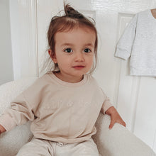 Load image into Gallery viewer, child sitting in a soft white chair wearing the crew sweatshirt in eggnog
