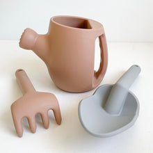 Load image into Gallery viewer, Peony silicone garden set showing peach watering can and rake and a grey spade
