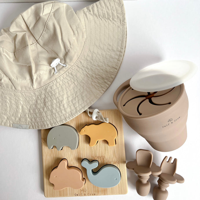 the everyday sunhat in cream with a silicone animal puzzle and a collapsible snack cup and easy grip spoon and fork in latte colour