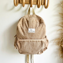 Load image into Gallery viewer, sand coloured corduroy backpack hanging on wooden hooks
