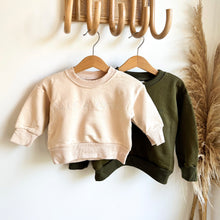 Load image into Gallery viewer, two crew sweatshirts in eggnog and khaki colours on hangers hanging on wooden hooks
