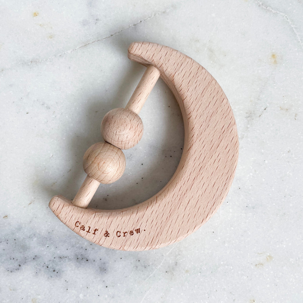 a wooden moon rattle with the calf & crew logo engraved on it