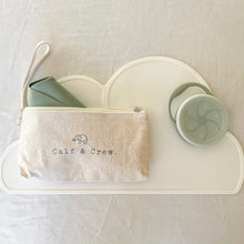 Load image into Gallery viewer, Sage bib foled in a beige pouch with Calf &amp; Crew logo, with a sage snack cup on a white placemat
