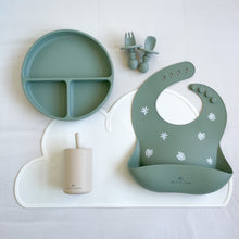 Load image into Gallery viewer, Divided plate, small fork and spoon, and silicone bib in forest green, laying on a white mat with a silicone straw cup in sand colour
