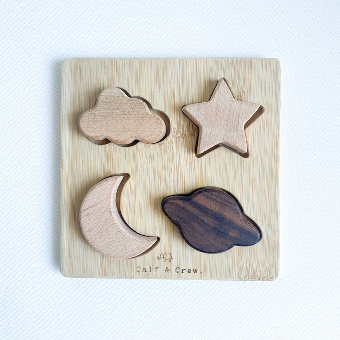 a wooden puzzle with a cloud, star, moon and planet as pieces