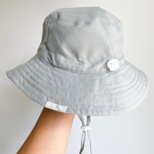 Load image into Gallery viewer, hand holding up sun hat in cloudy blue, showing the adjustable strap
