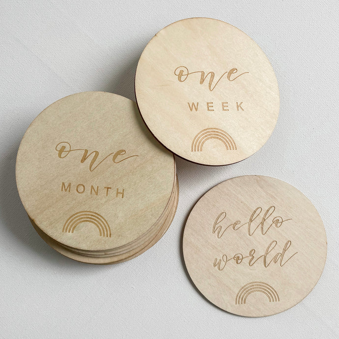 three wooden discs with milestones and a rainbow engraved on them