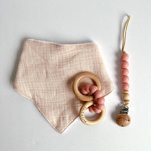 Load image into Gallery viewer, Baby pink coloured muslin bib with a wooden silicone ring teether and silicone dummy clip in blush
