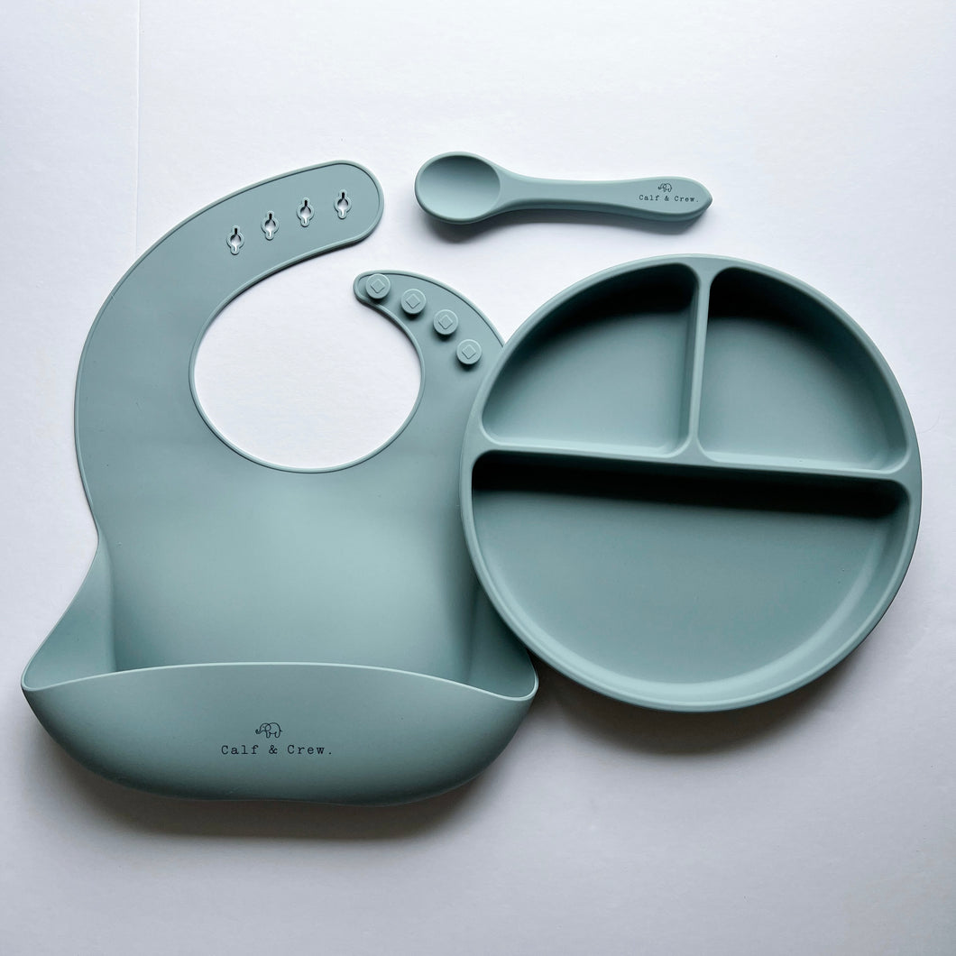 a silicone bib, suction divider plate and a silicone spoon in baby blue colour