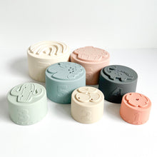 Load image into Gallery viewer, the pastel silicone stacking cups scattered all showing their different shape moulds and numbers
